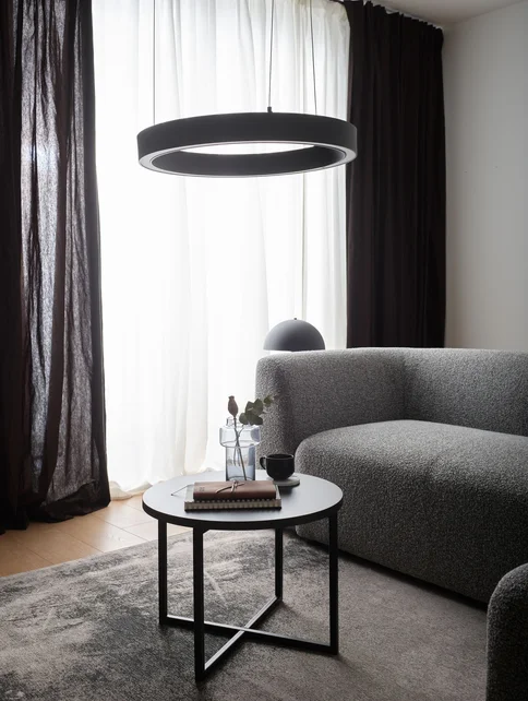 Szara sofa i okrągła lampa